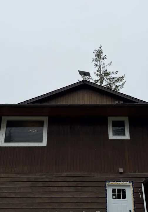 Starlink dish mounted near the roof peak of a wood-sided home