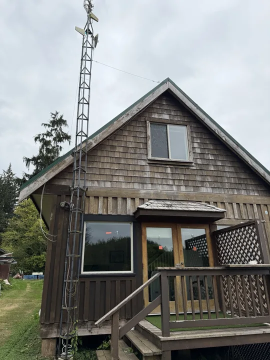 Starlink dish mounted on a tower beside a wooden cabin