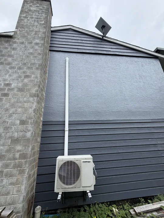 Starlink dish mounted high on the exterior wall of a house