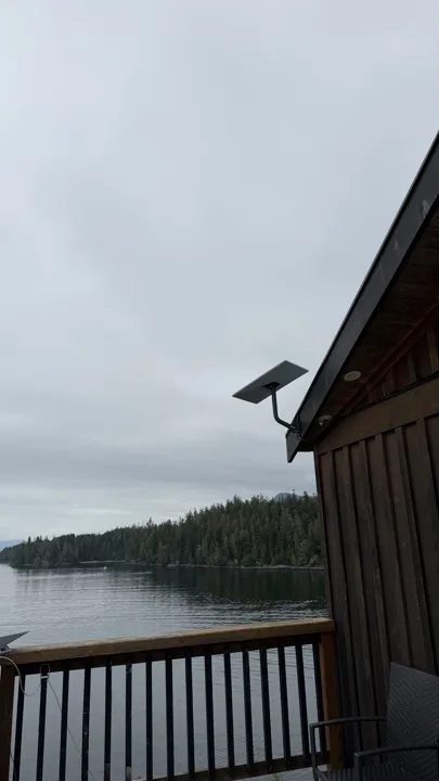 Starlink dish mounted below the roof edge of a waterfront home